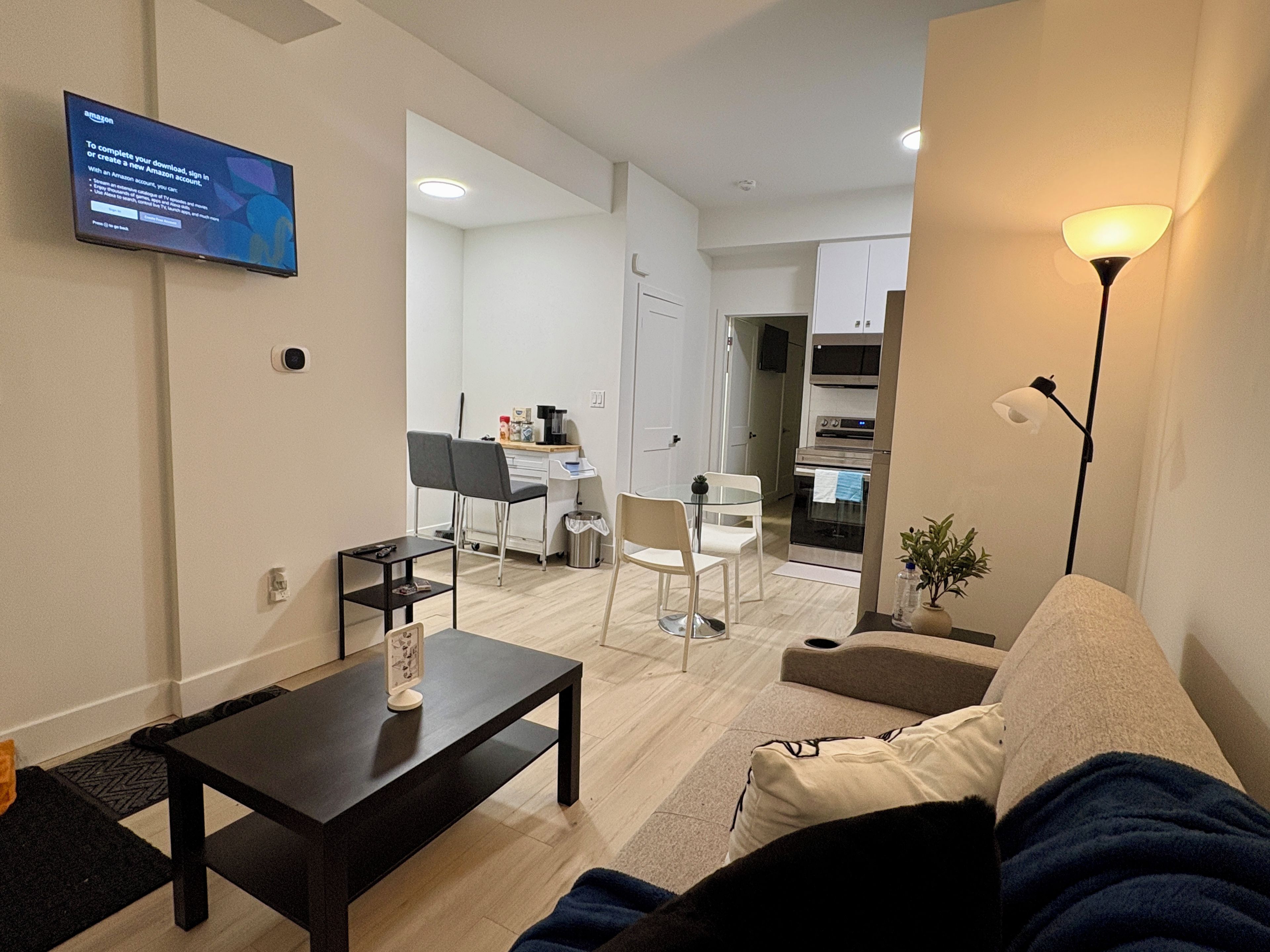 A modern living room with a sofa, a coffee table, and a TV mounted on the wall displaying an Amazon sign.