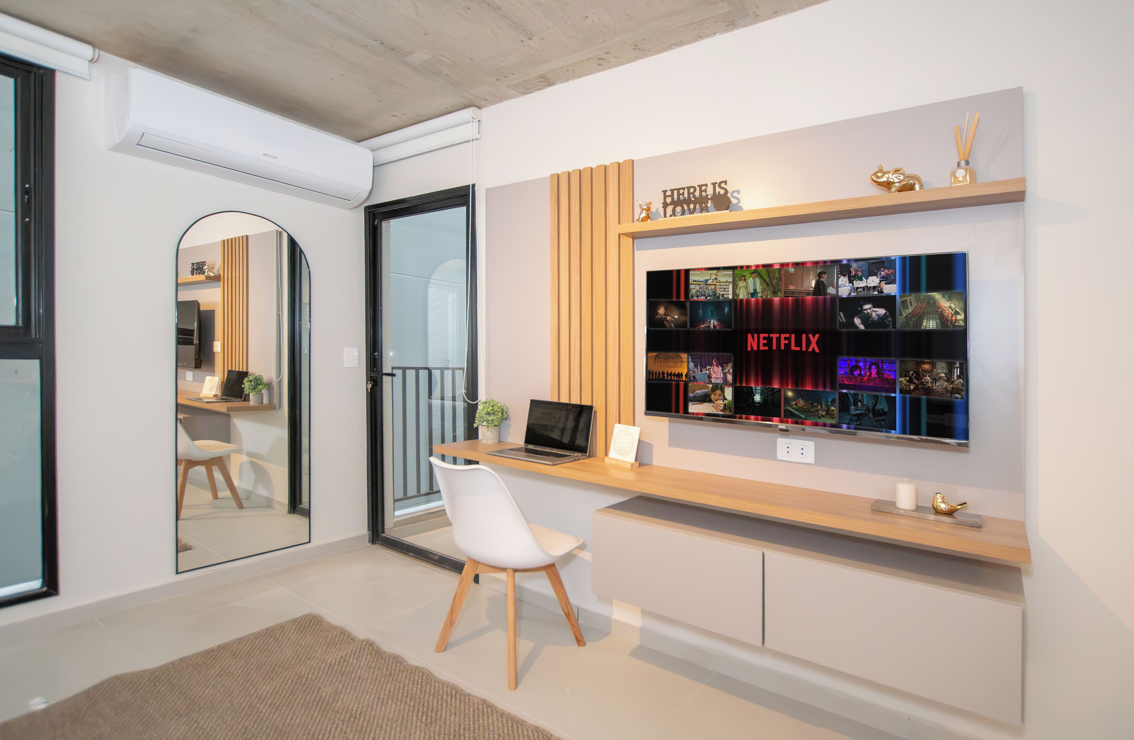 Un espacio de oficina moderno con un escritorio, una silla y una pantalla mural con contenido de Netflix.