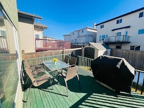 Une terrasse extérieure couverte, avec une table et des chaises, un barbecue et une clôture en bois.