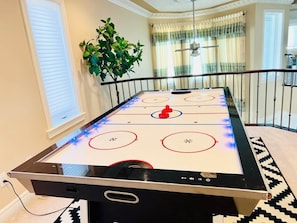 Une pièce avec un jeu de hockey sur table, une plante en pot et une vue sur un balcon.