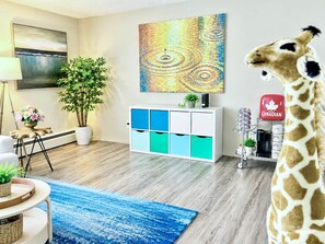 Een moderne woonkamer met een witte kast, een groot schilderij, een potplant en een girafbeeldje.