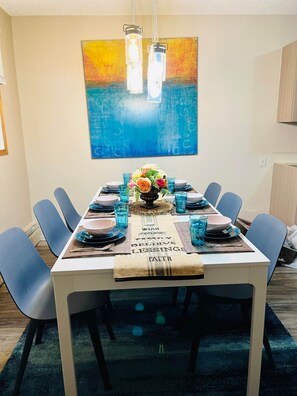 A dining area with a table set for six, blue chairs, a decorative centerpiece, and a wall painting. - Family Baby&Kid Friendly*Close toUofA*Kingbed*3BR* (Edmonton)