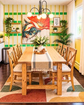 A dining area with a wooden table, chairs, a painting, and a wall with green and yellow stripes. - Funky family-friendly 3BR, king bed near U of A (Edmonton)