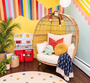 A cozy room with a wicker chair, a small kitchenette, and a colorful striped wall. - Funky family-friendly 3BR, king bed near U of A (Edmonton)