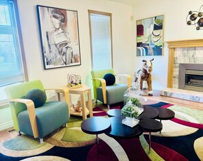 A modern living room with green armchairs, a fireplace, abstract art, and a decorative dog statue. - KidsParadise*Kingbed*NearWEM*BabyFamilyKid Frienly (Edmonton)