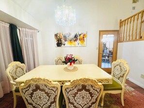 Ein Esszimmer mit einer Chandelüster, einem Tisch und vier Stühlen mit aufwendigen Verzierungen.