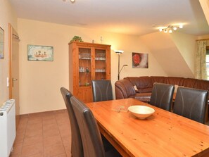 A dining area with a wooden table, black chairs, a cabinet with glassware, and a painting on the wall. - 1.6/t1 Holiday Home Park \"freesenbruch\" (Zingst)