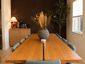 A wooden dining table with a vase of dried plants in the center, surrounded by upholstered chairs. - Wellness Retreat: Pool, Hot Tub, Mini Golf, Outdoor Shower + Old Town Scottsdale (Scottsdale)