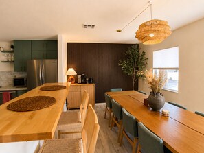 A modern kitchen with a wooden dining table, chairs, and a hanging light fixture. - Wellness Retreat: Pool, Hot Tub, Mini Golf, Outdoor Shower + Old Town Scottsdale (Scottsdale)