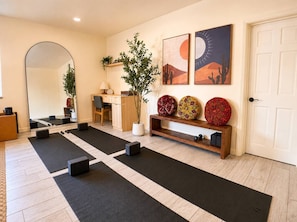 A room with a yoga mat layout, a mirror, a wooden bench with decorative items, and a door. - Wellness Retreat: Pool, Hot Tub, Mini Golf, Outdoor Shower + Old Town Scottsdale (Scottsdale)