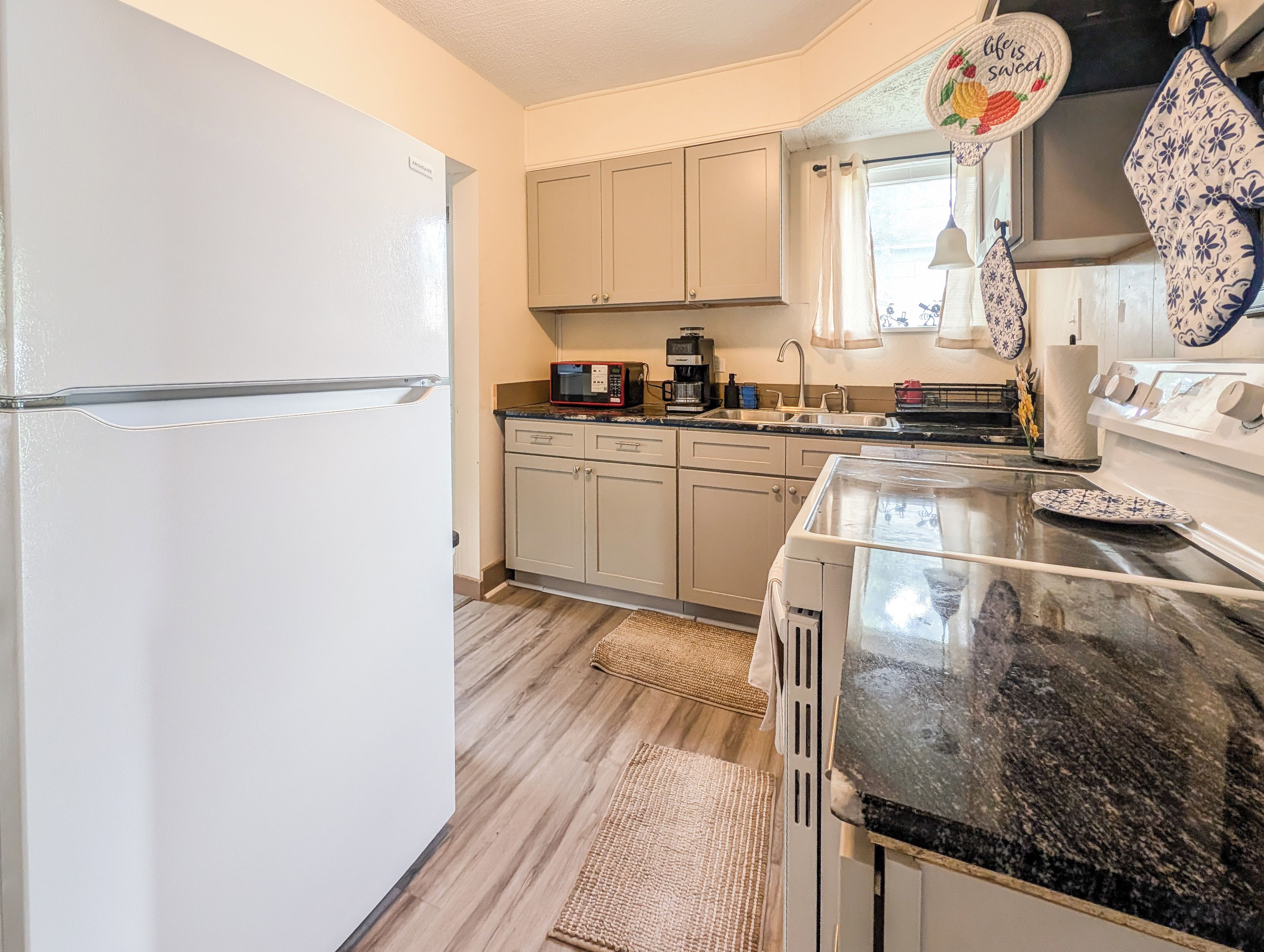 A kitchen with a refrigerator, microwave, coffee maker, and a sink.