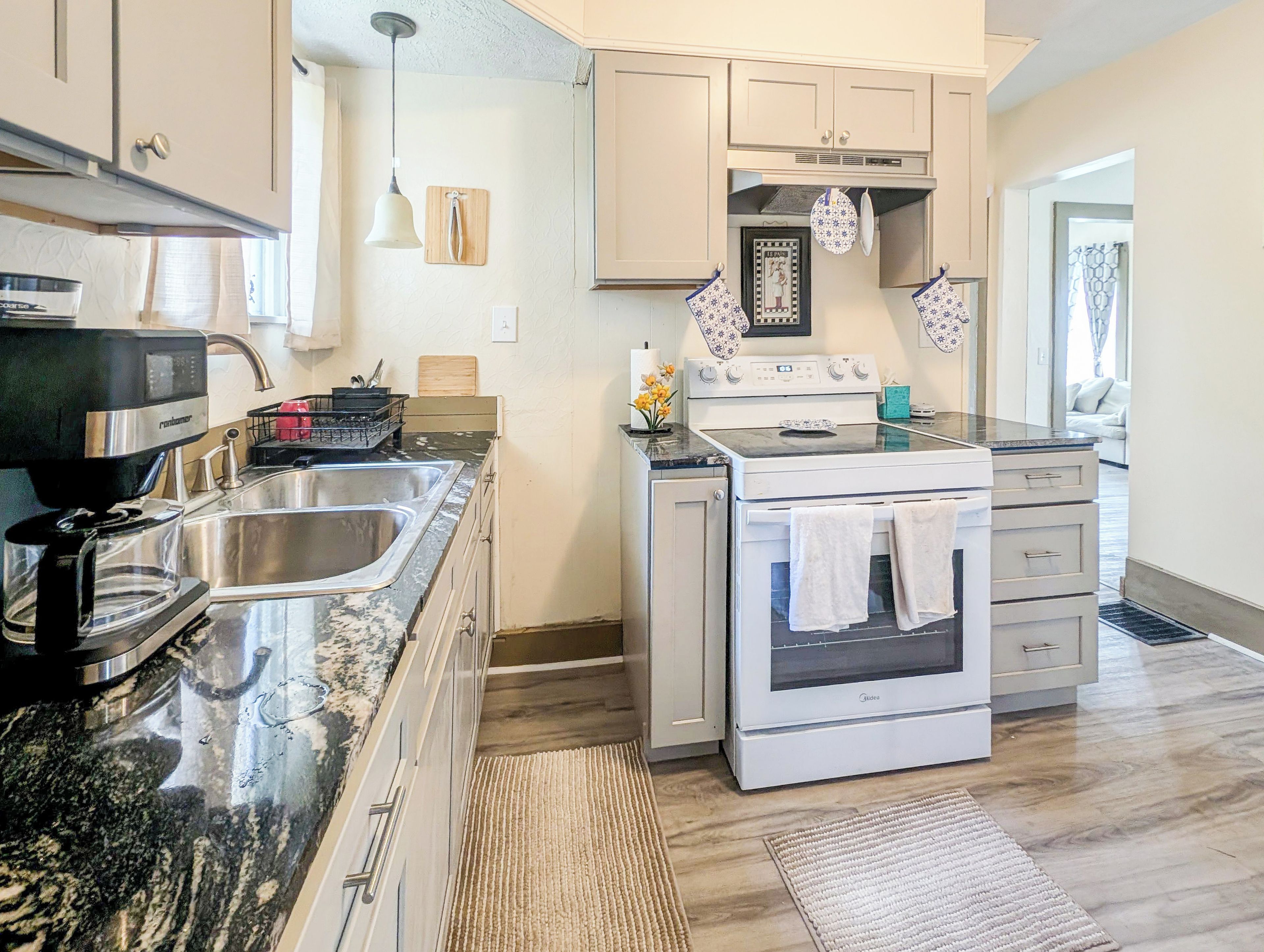 A modern kitchen with a coffee maker, double sink, stove, and oven.