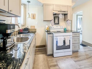 A modern kitchen with a coffee maker, double sink, stove, and oven.