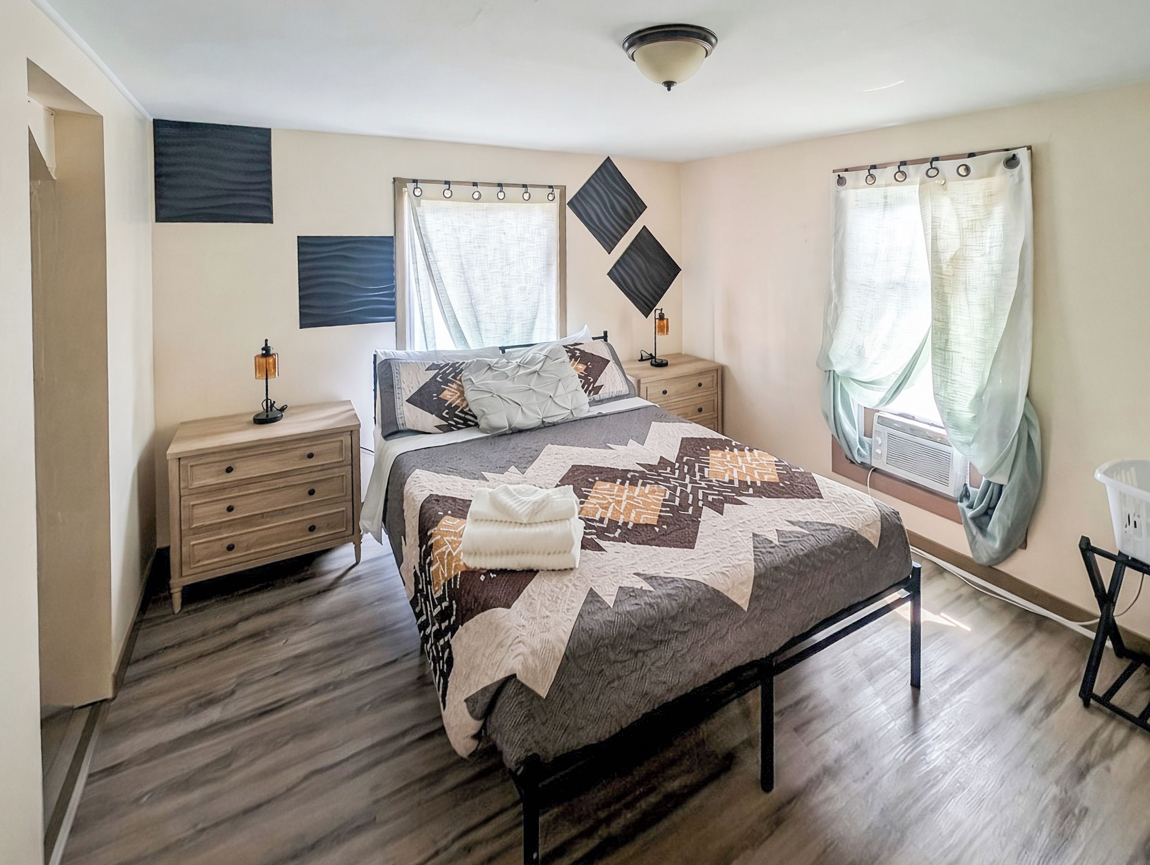 A bedroom with a bed, bedside tables, a lamp, and a window with curtains.