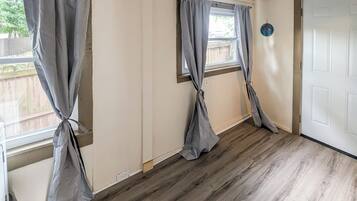 A room with two windows, wooden flooring, and a white door.