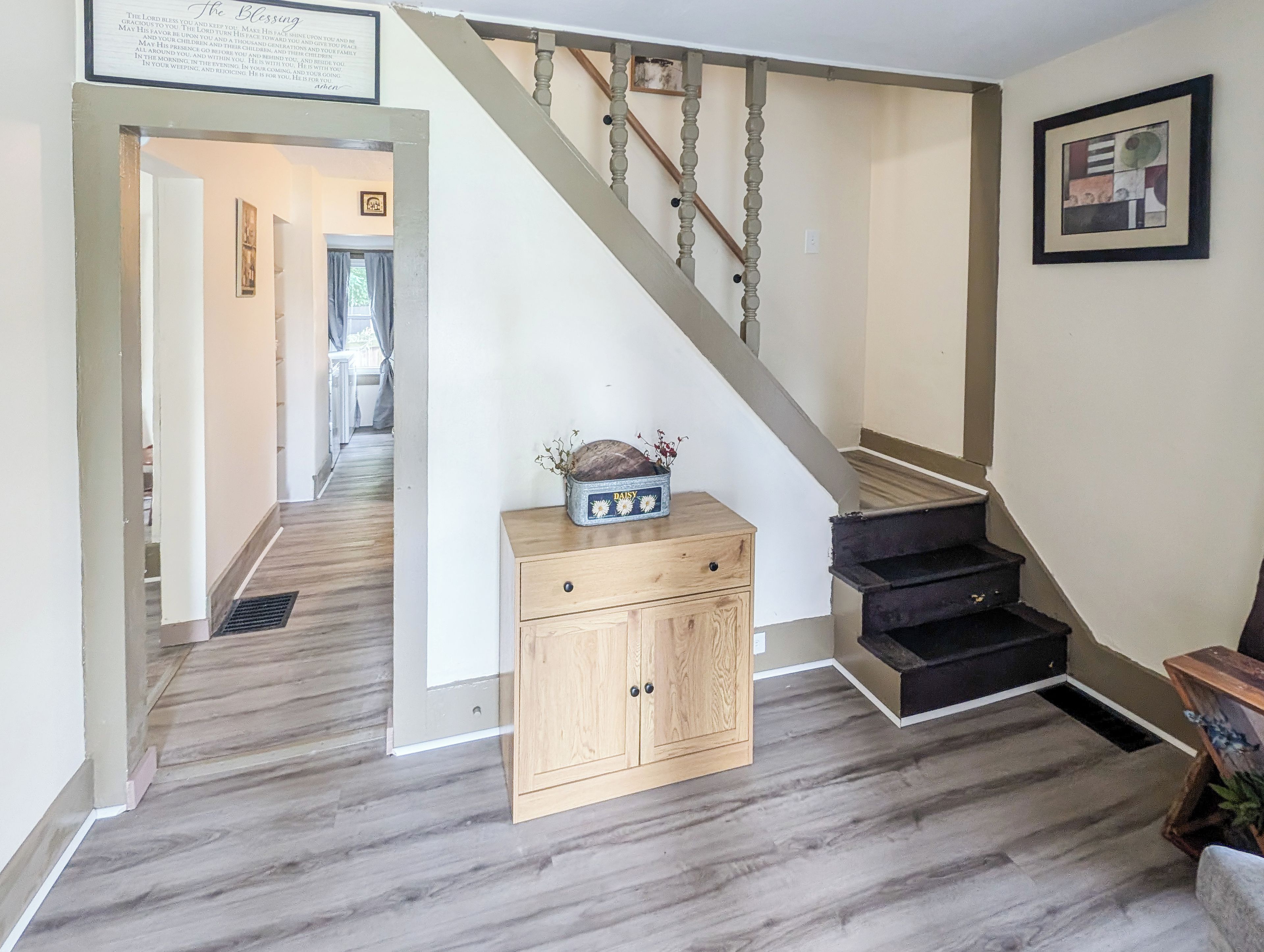 A staircase with a wooden handrail and a black carpeted landing.