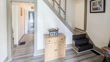 A staircase with a wooden handrail and a black carpeted landing.