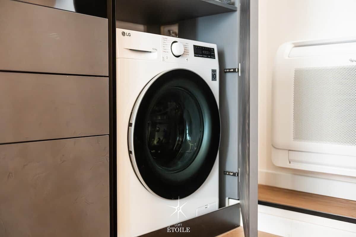 Een wasmachine met voorlader en bedieningspaneel, met een witte droger in een wasserij.