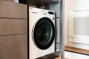 A front-loading washing machine with a control panel and a white dryer in a laundry room. - Loft Étoile - Elegance in the Heart of San Benedetto (Cagliari)