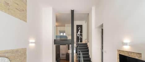 A modern interior with a staircase, a fireplace, and a wall-mounted artwork.