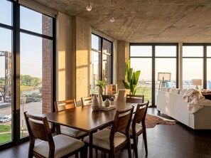A spacious dining area with a large table and chairs, a sofa, and a view of the outside. - Lakefront+Parking+Balcony (Cleveland)