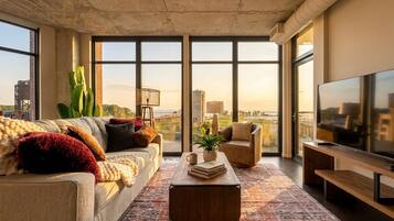 A modern living room with a large window, a sofa, a coffee table, and a TV.