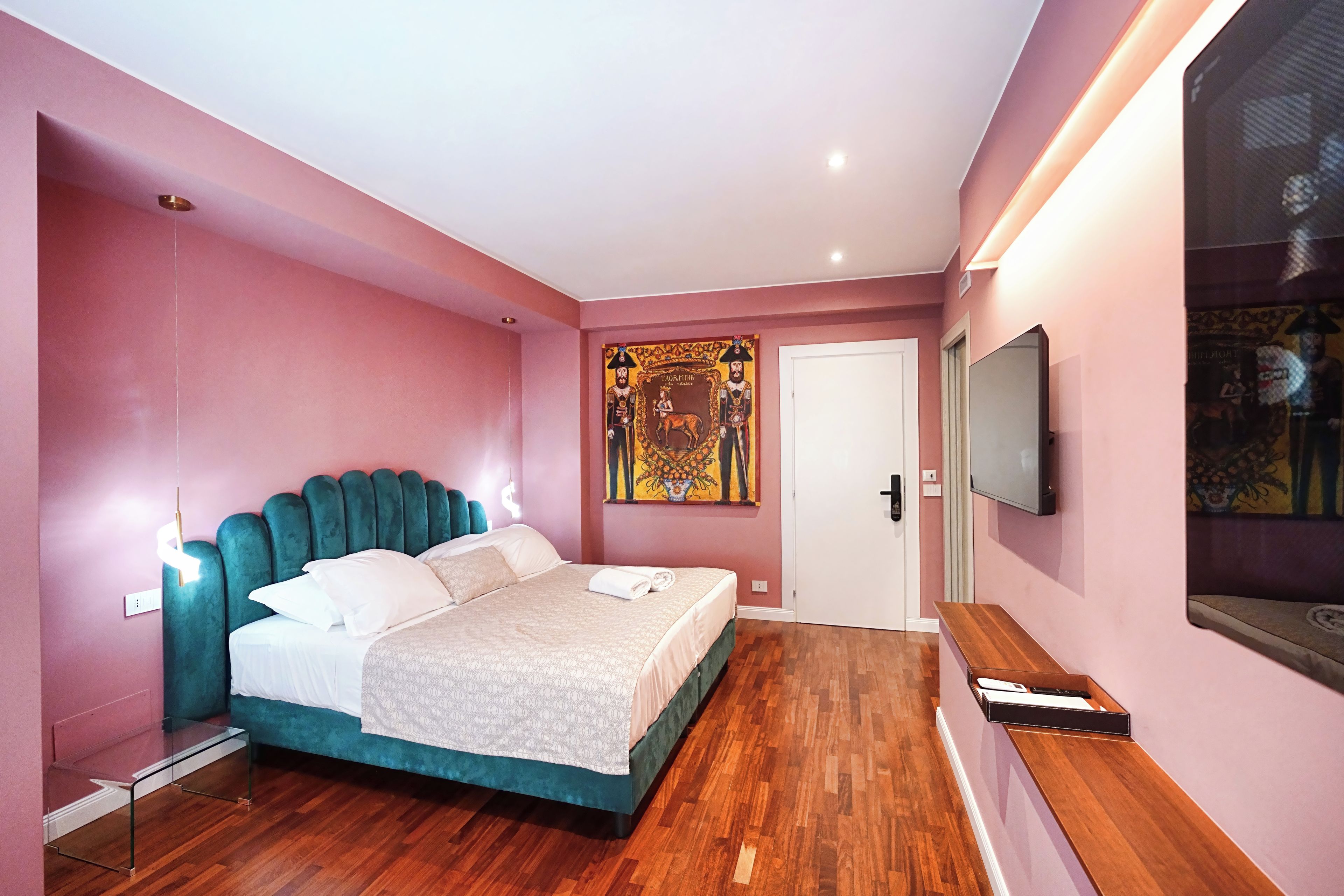 Ein modernes Schlafzimmer mit einem moosgrünen ausgestatteten Bett, einem flachbildfernseher an der Wand und einer Holzbank.