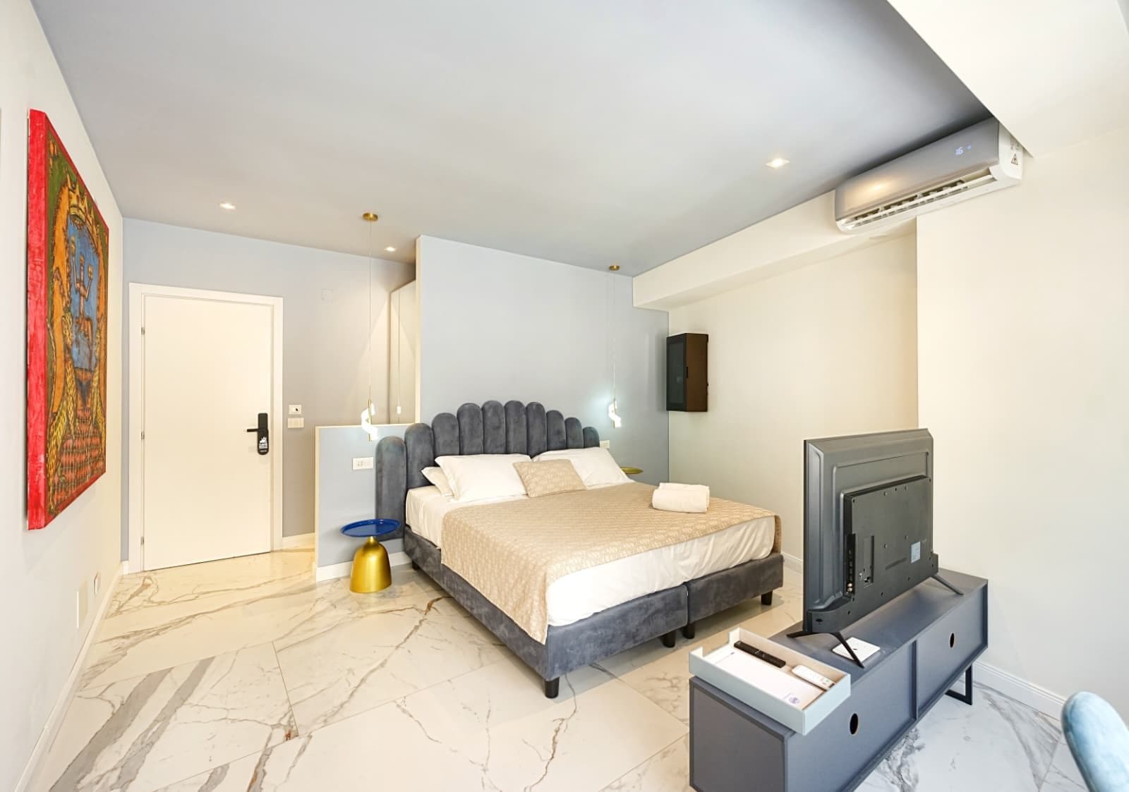 Une chambre à coucher moderne, équipée d’un lit, d’une télévision et d’un bureau.