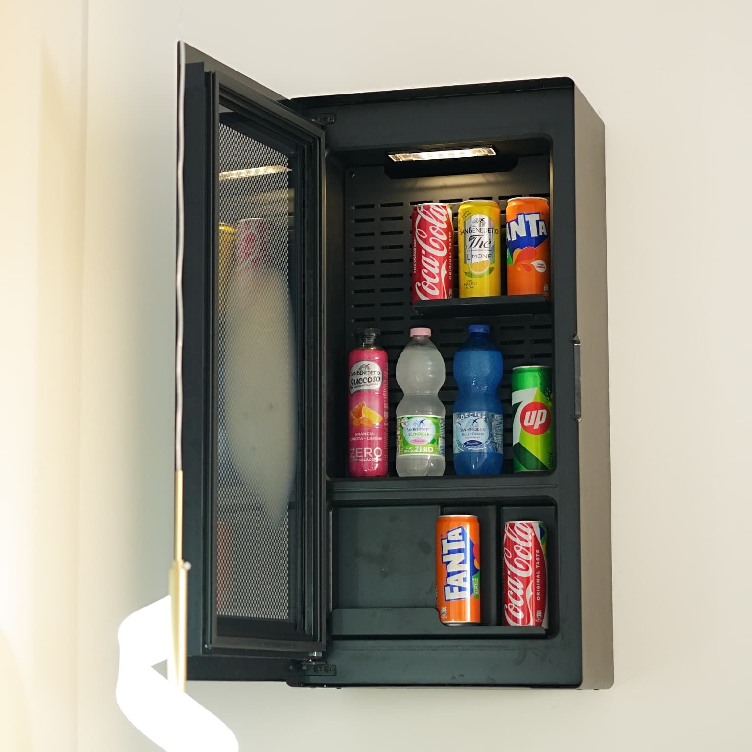 Un refrigeratore per bevande con diversi tipi di bibite, tra cui lattine e bottiglie.