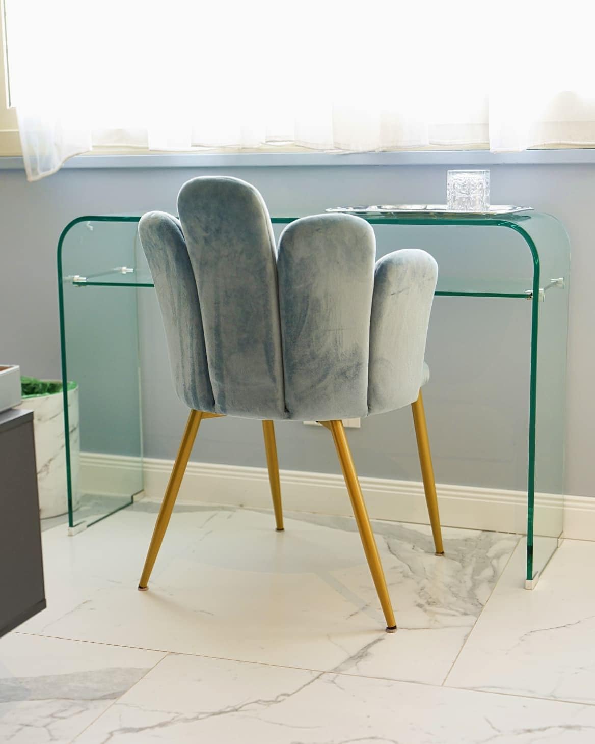Una silla de diseño original, ubicada frente a un escritorio de vidrio con estructura metálica.