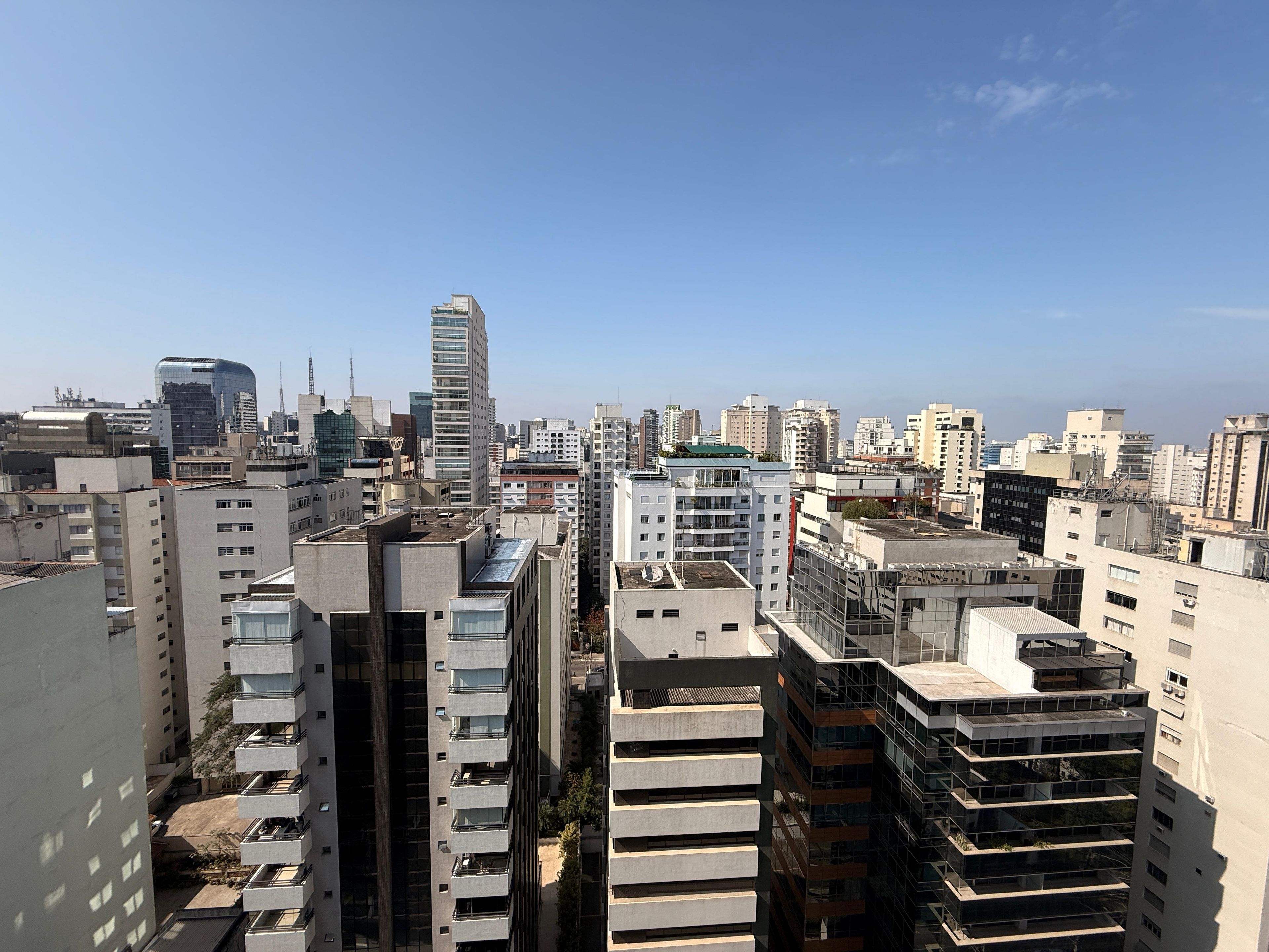 Zona urbana com edifícios altos e modernos, incluindo um arranha-céu com design curvilíneo.