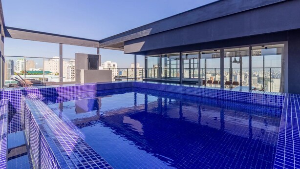 Una piscina en la azotea con vistas a la ciudad, rodeada de paredes de vidrio y arquitectura moderna.