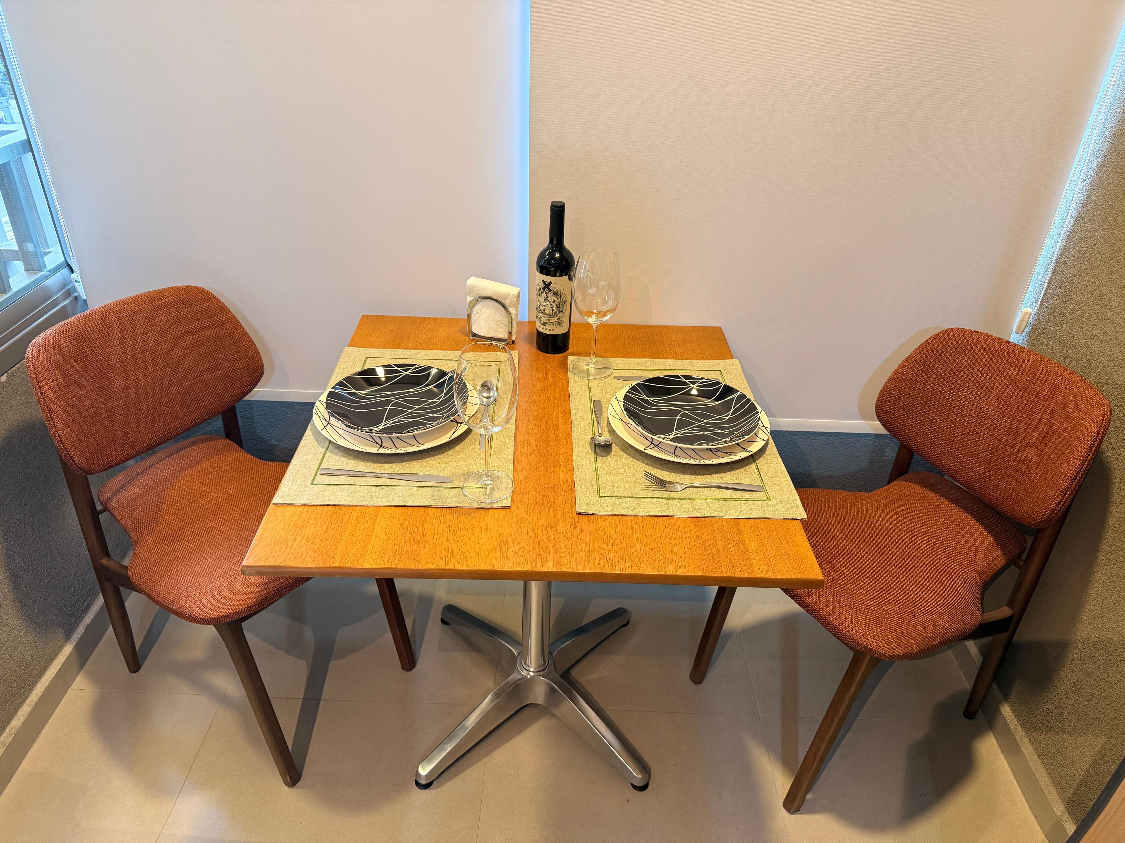 Une table à manger avec deux chaises, une bouteille et un verre.