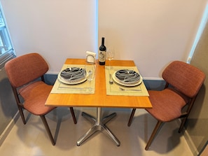 A dining table with two chairs, a bottle, and a glass. - New Studio in Jardins | 2 Blocks from Paulista | Pool, Gym & Coworking (São Paulo)