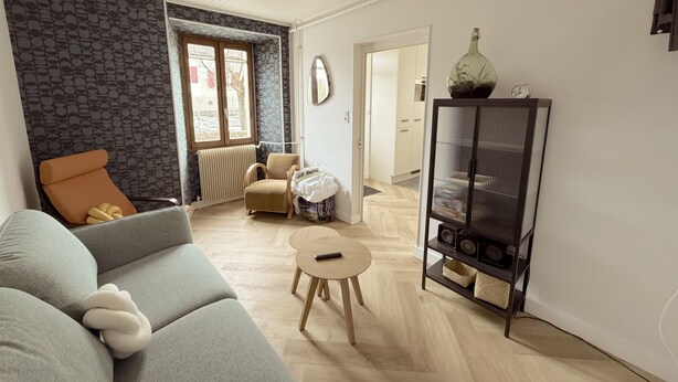 A living room with a sofa, a small round table, a cabinet with speakers, and a radiator. - Holiday Home 'Étape À Monestier Du Percy' with Mountain View and Private Terrace (Monestier-du-Percy)