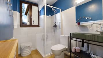 Een badkamer met douche, toilet, wastafel en spiegel.