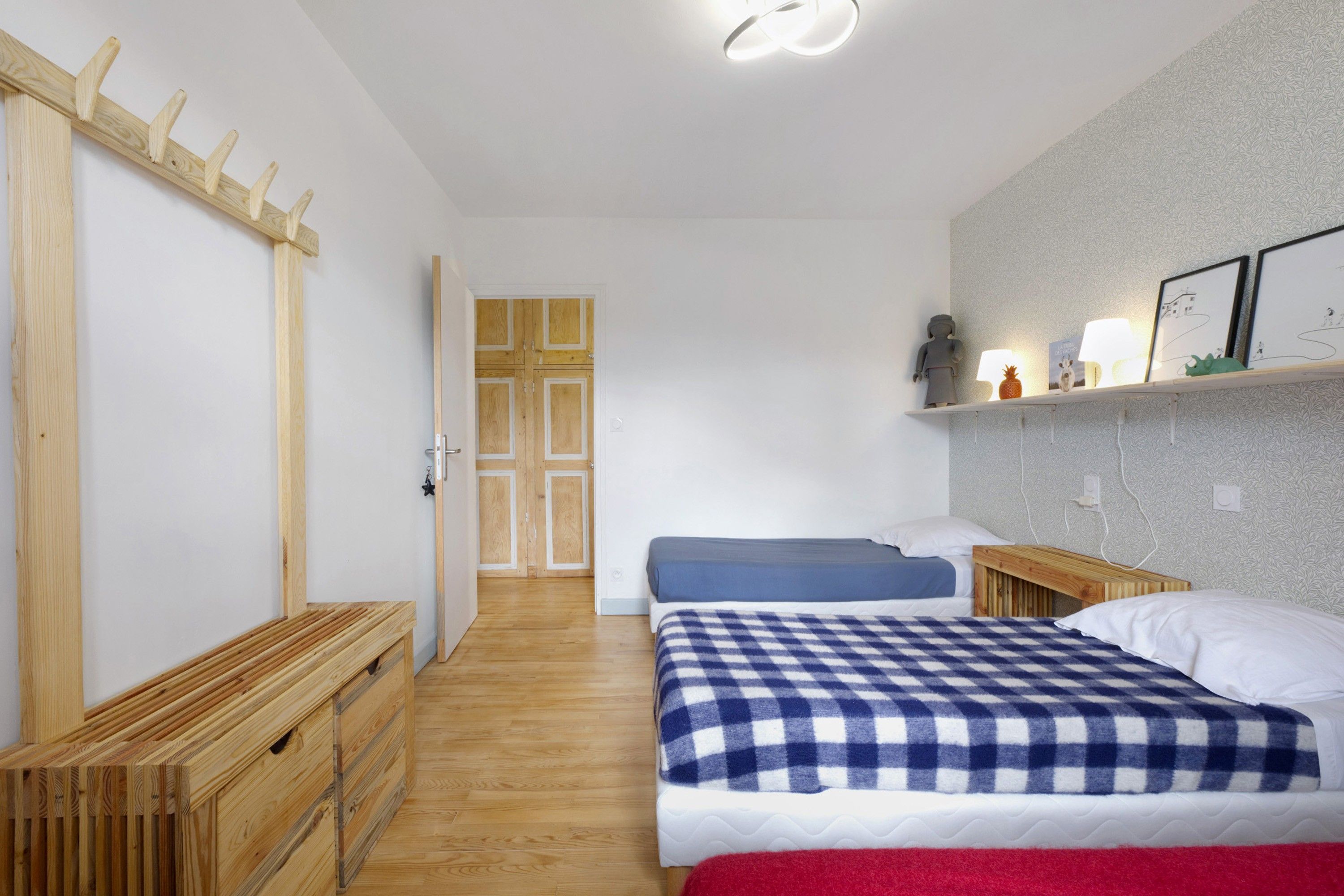 Een slaapkamer met een bed, een bankje, een deur en een plank met decoratieve spullen.
