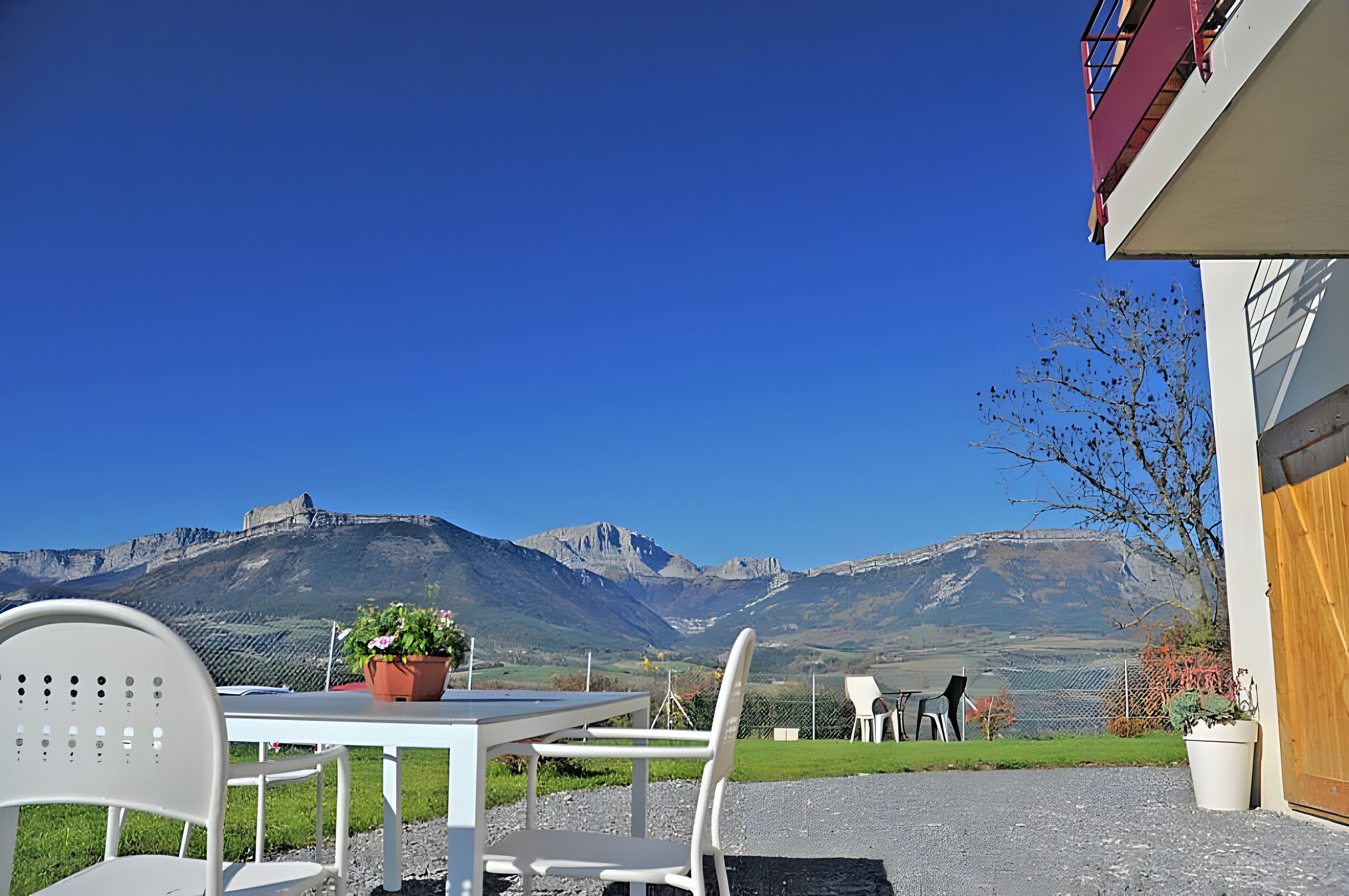Une terrasse avec des sièges extérieurs, une vue sur les montagnes et un bâtiment doté d’un balcon.