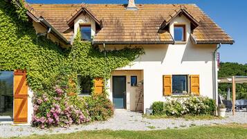 A two-story house with a sloped roof, a front entrance, and a small porch area.