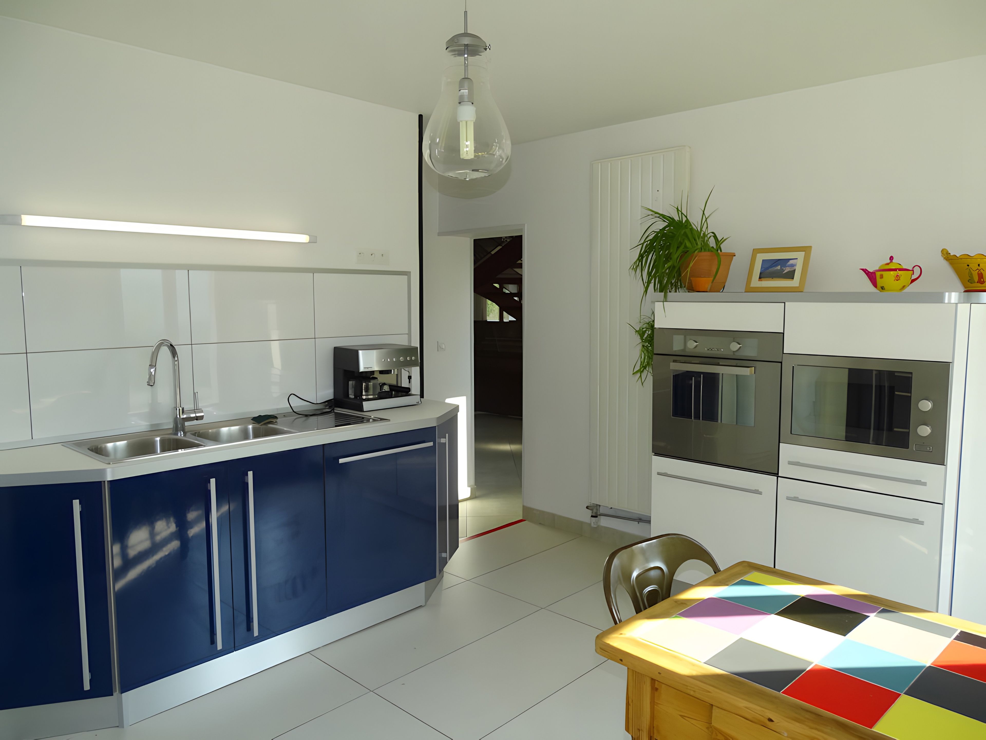 A modern kitchen with a central island, built-in appliances, and a dining area with a colorful table.