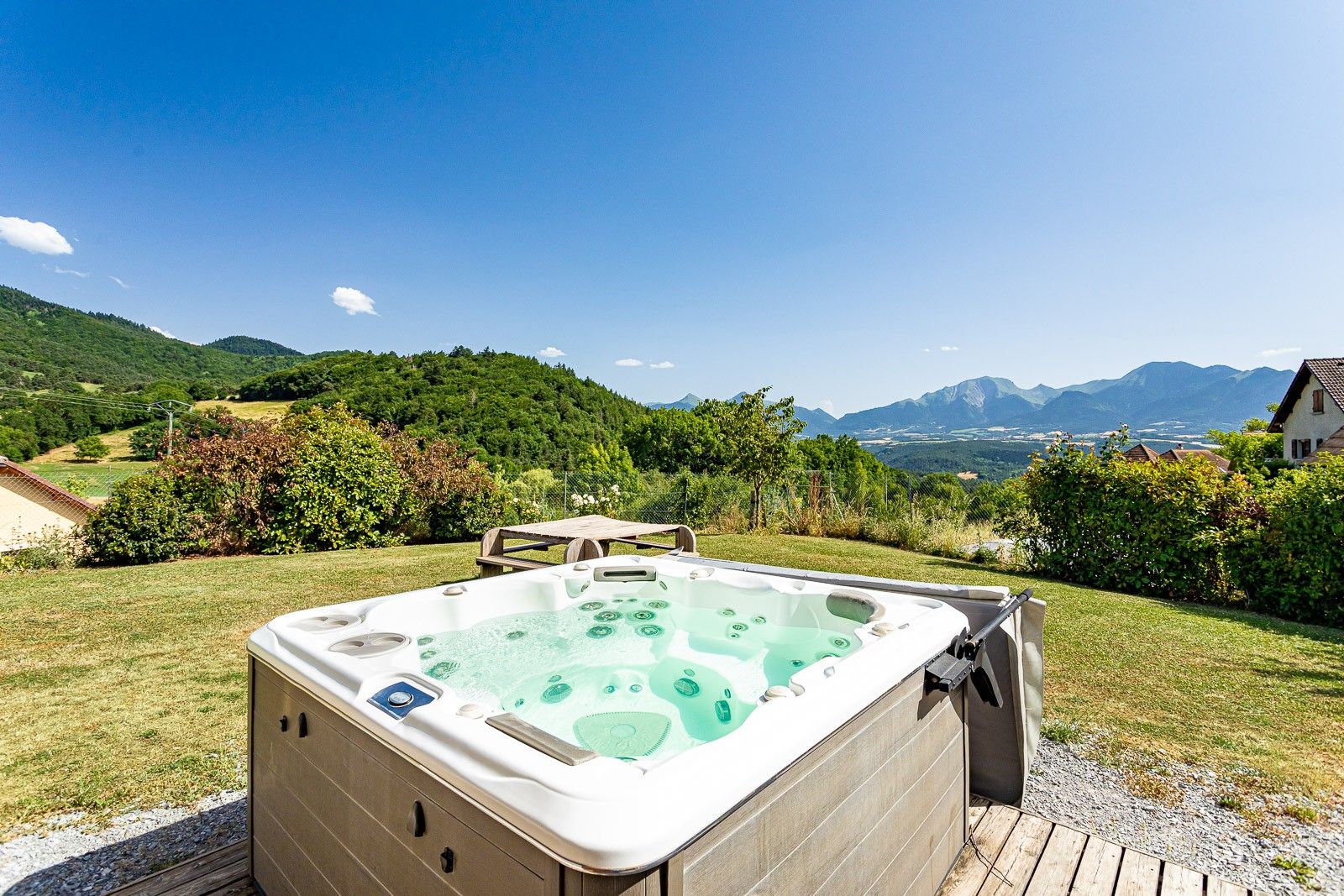 A hot tub in a garden with a mountainous backdrop.