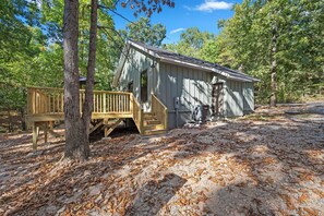 A cabin with a wooden deck and stairs leading to a door. - Lovely 2-bedroom 2 bath brand new home on 5 acres just outside of town (Gravette)
