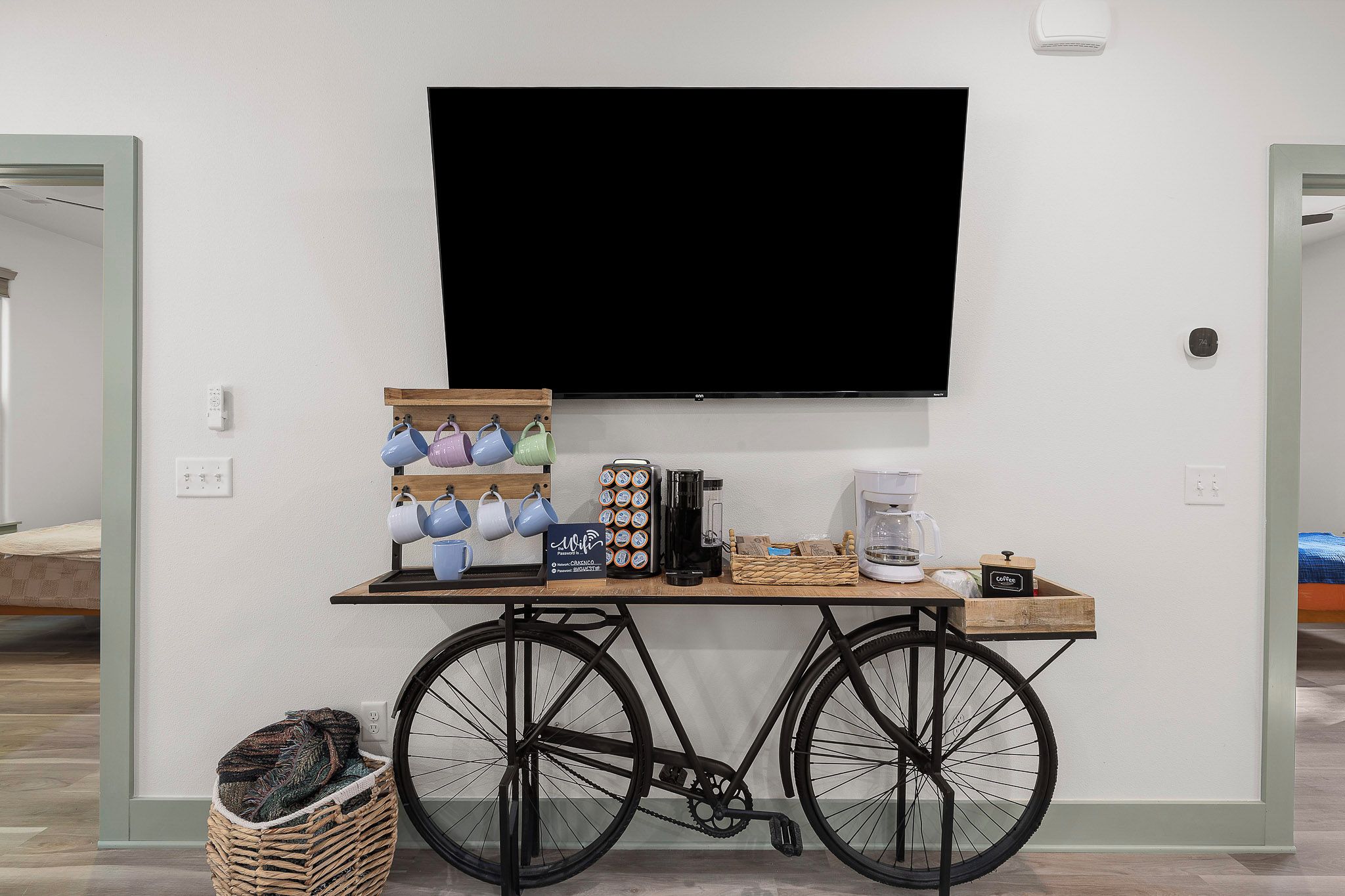 Une chambre dotée d’un téléviseur fixé au mur, d’un coin café avec une machine à café, d’un panier et d’un plateau avec des tasses.