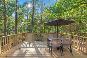 Eine Terrasse im Freien mit Holzgeländer, Tisch, Stühlen und Sonnenschirm.