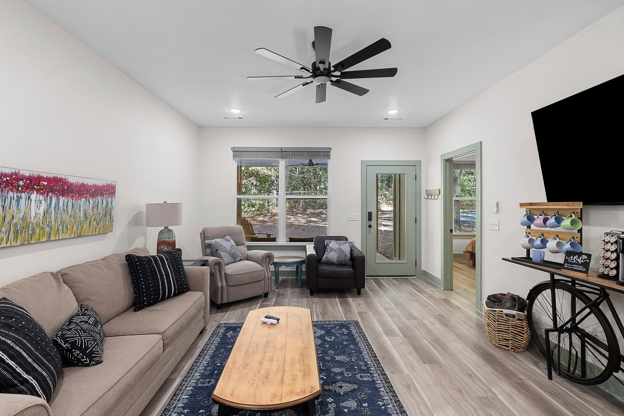 A modern living room with a sofa, armchairs, a coffee table, and a ceiling fan.