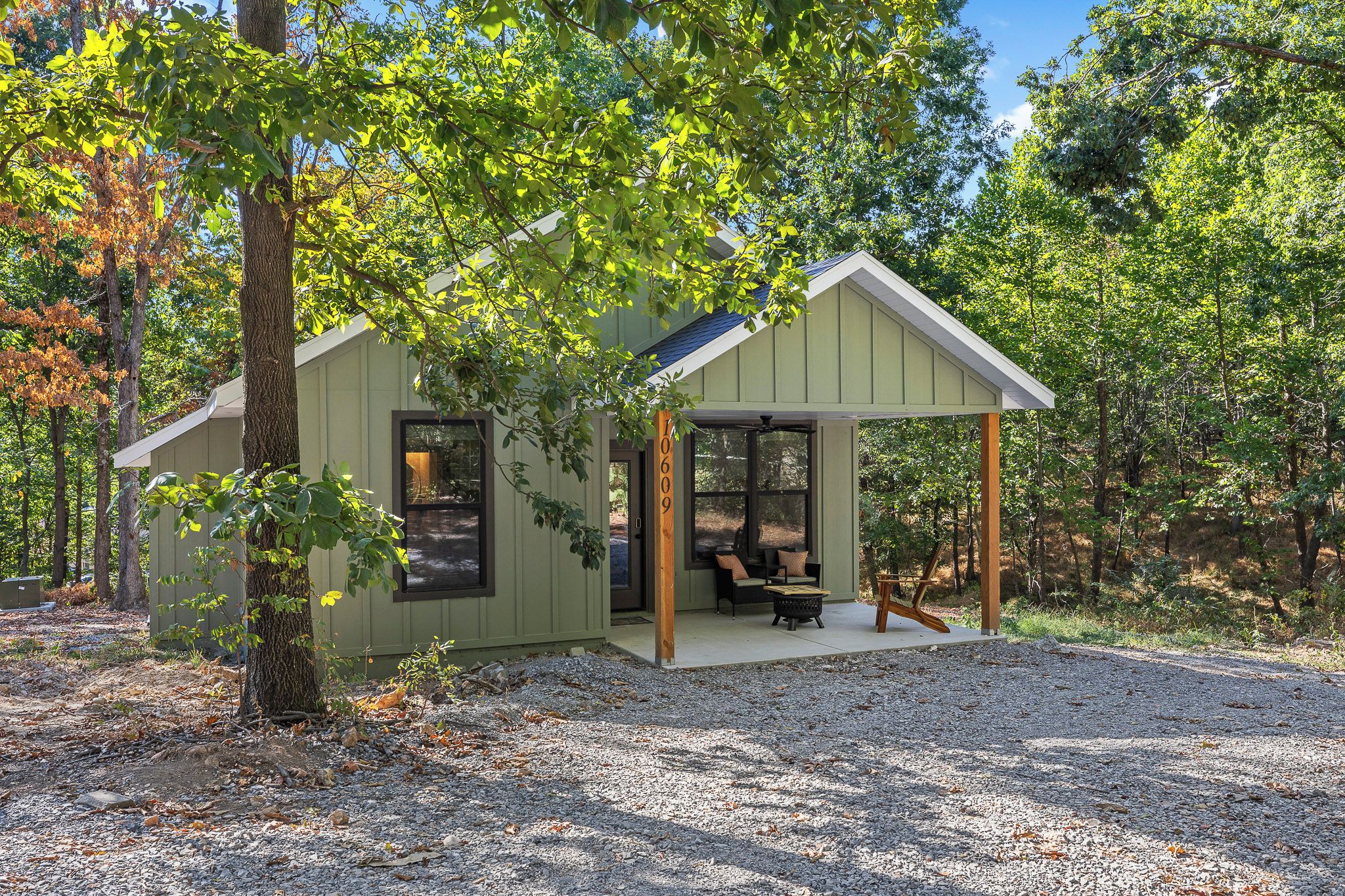 Une petite cabane à un seul étage, dotée d’une véranda et entourée d’arbres.