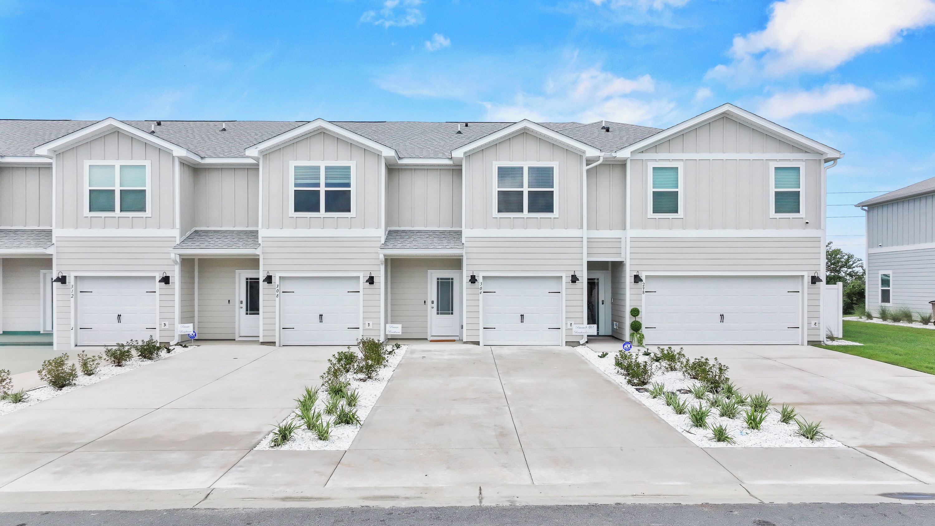 A row of two-story townhouses with attached garages and a central entrance.
