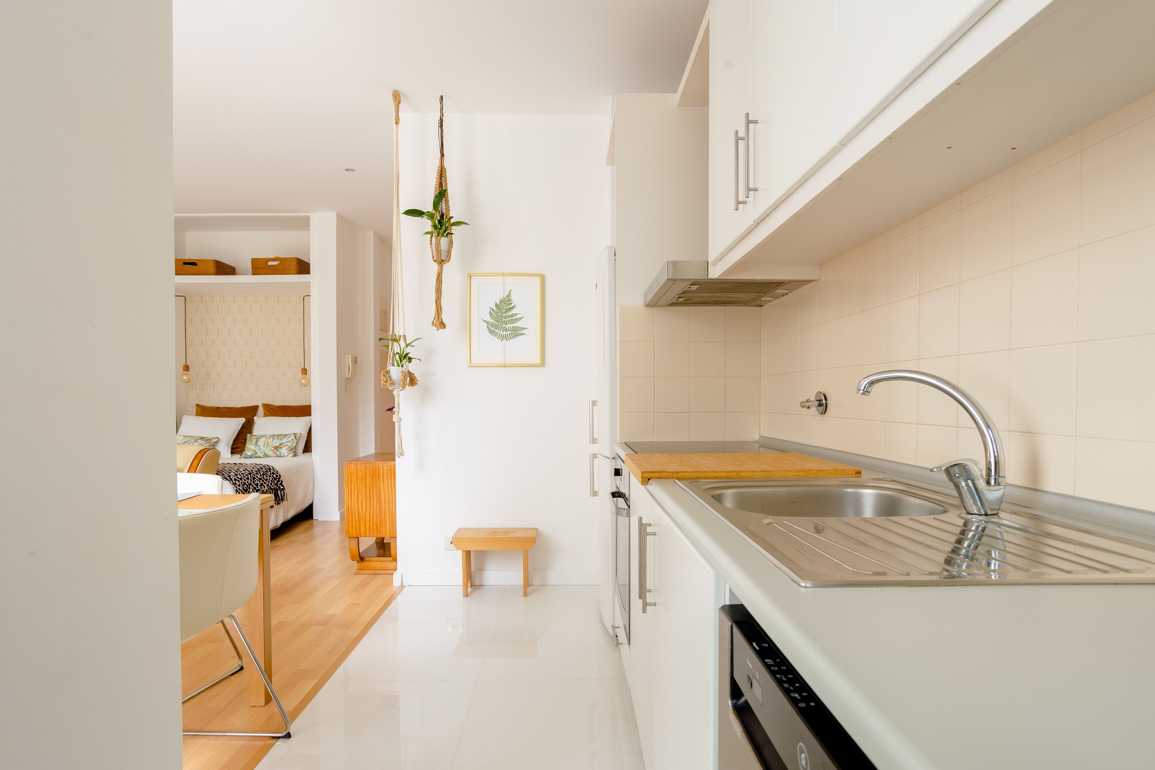 A modern kitchen with white cabinetry, a stainless steel sink, and a wooden countertop.