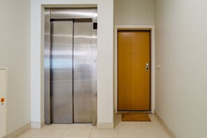 Ein Flur mit einem metallenen Aufzug und einer Holztür.