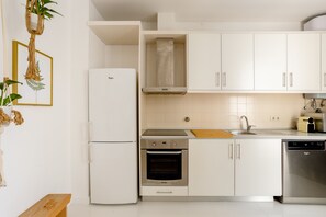 Eine moderne Küche mit weißen Schränken, einem eingebauten Ofen, einer Spülmaschine und einem Kühlschrank.